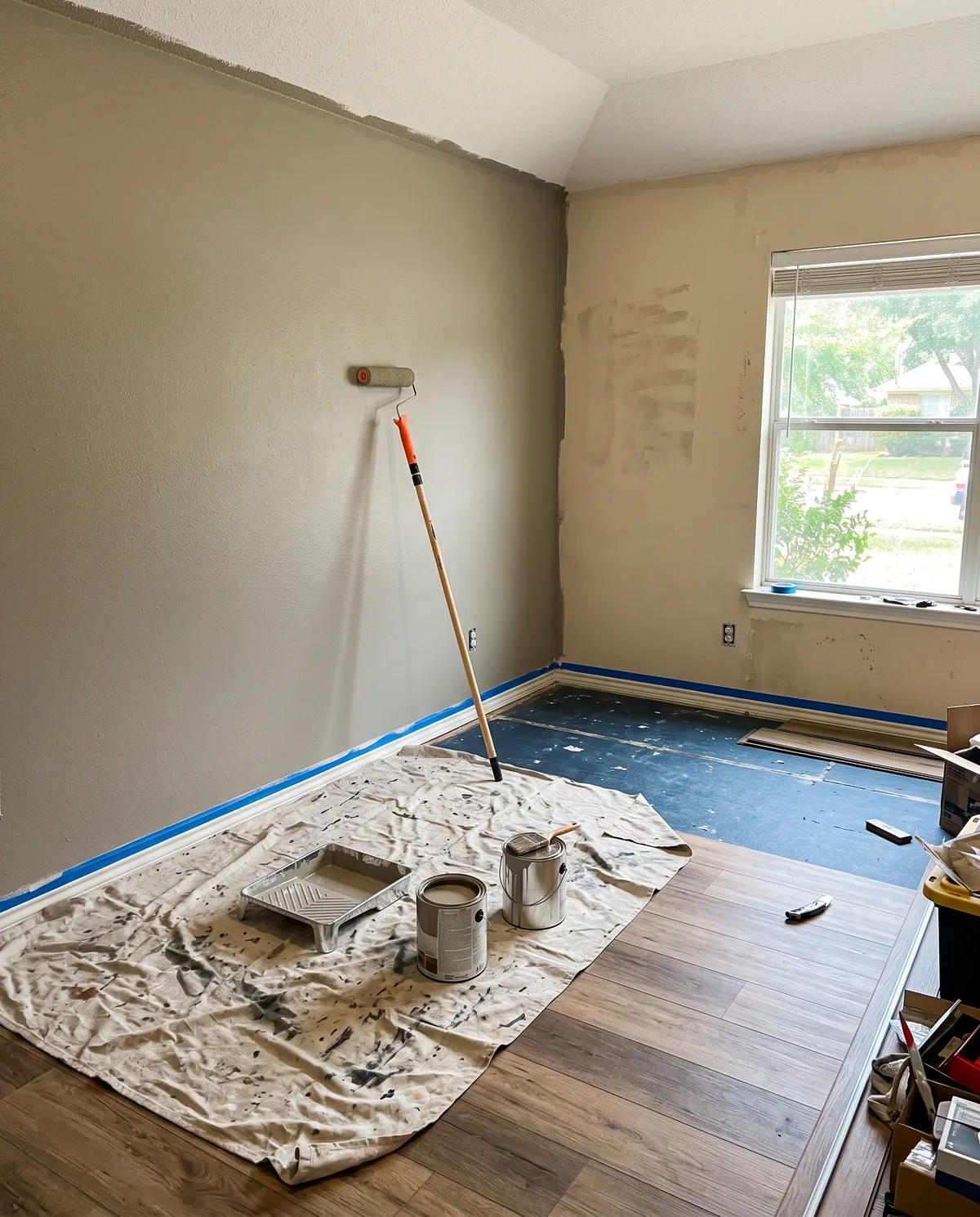 Room being painted over drop cloths, with new wood-look flooring in place