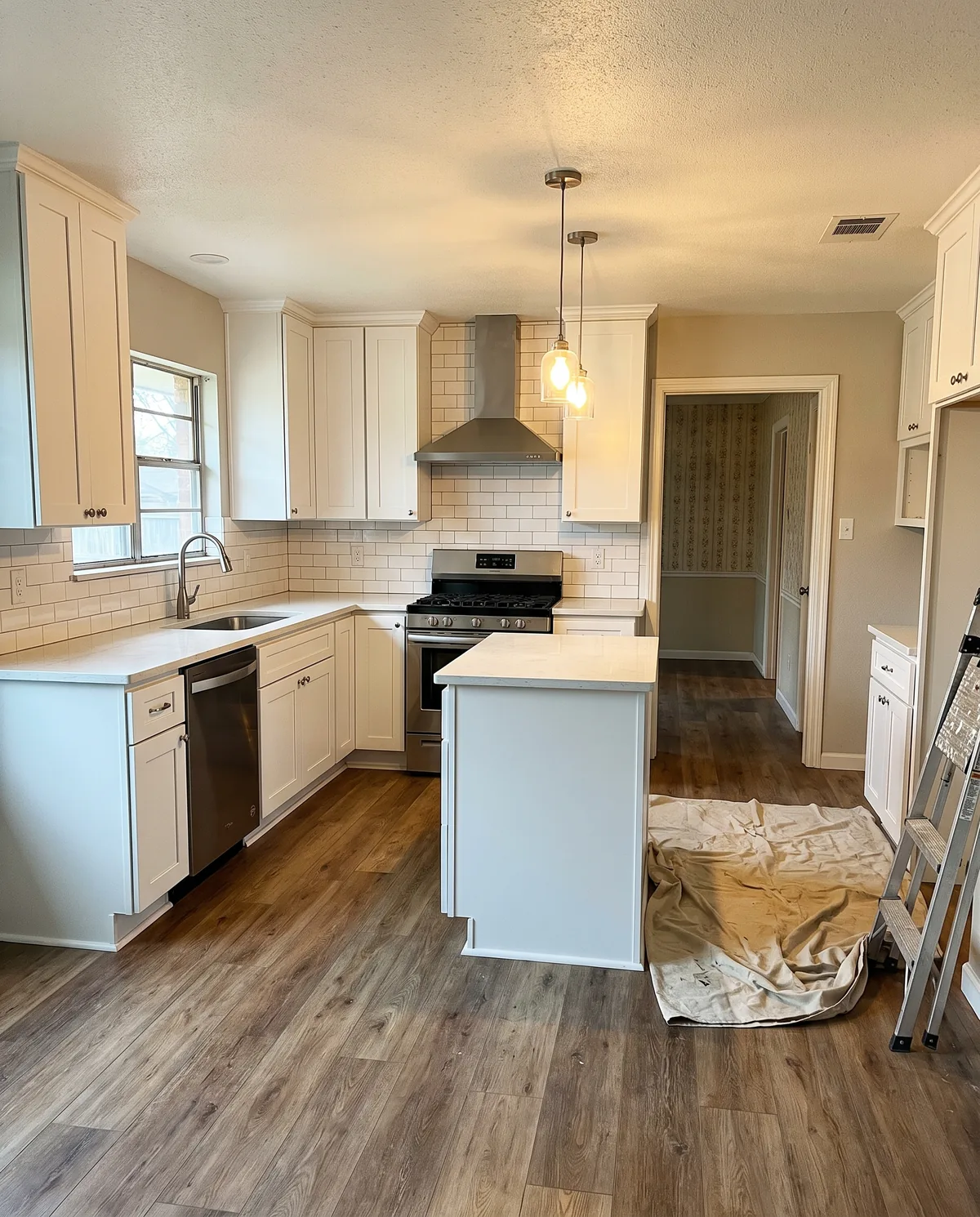 Kitchen renovation with white cabinets, an island and protected work surfaces